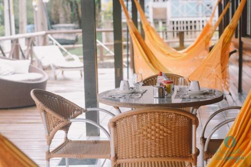 a table and chairs on a porch with hammocks at Pousada da Maga in Fernando de Noronha