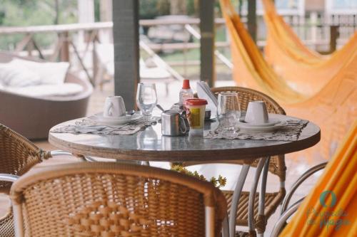 uma mesa exterior com cadeiras e uma mesa com pratos e copos em Pousada da Maga em Fernando de Noronha