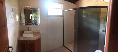 een badkamer met douche, wastafel en spiegel bij Sitio damasio. Casas em Arraial d'Ajuda in Arraial d'Ajuda