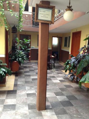 a sign on a pole in a room with plants at Hotel Palacio in Uruapan del Progreso