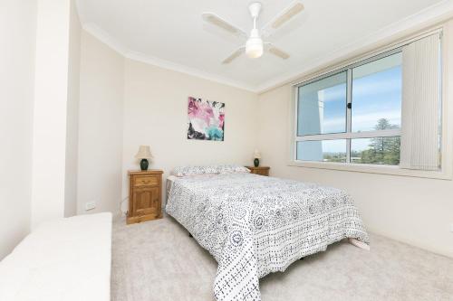 a white bedroom with a bed and a window at Mirage 502 - linen not included in Tuncurry