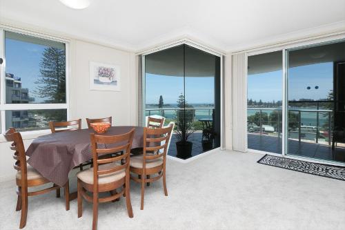 a dining room with a table and chairs and windows at Mirage 502 - linen not included in Tuncurry