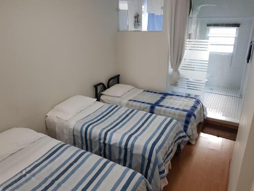 um quarto com três camas com lençóis listrados em Av. Paulista Trianon MASP em São Paulo