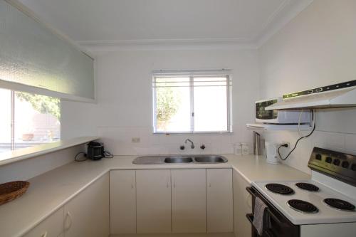 a white kitchen with a sink and a stove at Ocean Views in Huskisson