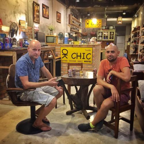 two men sitting in chairs at a table in a store at OK CHIC PHUKET HOSTEL in Phuket Town