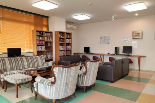 a waiting room with couches and chairs in a library at Hotel Sunrise in Onagawa
