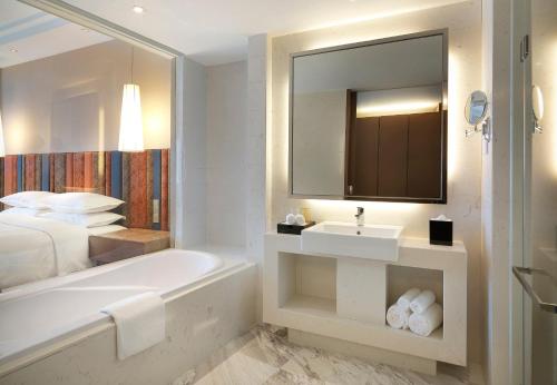 a bathroom with a tub and a sink and a bed at Four Points by Sheraton Bijie in Bijie