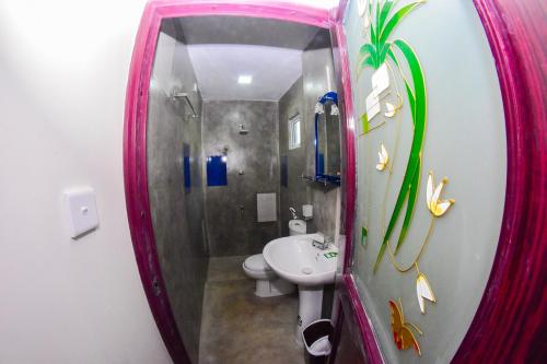 W łazience znajduje się umywalka, toaleta i lustro. w obiekcie Wattle Inn w Negombo
