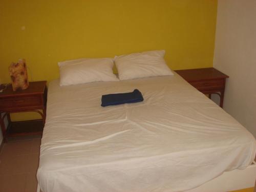 a large white bed with a blue book on it at Dre Broeders Apartments Juan Dolio in Juan Dolio