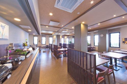 a restaurant with wooden tables and chairs and tables at Hotel Route-inn Yamaguchi Yuda Onsen in Yamaguchi