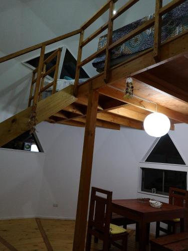 a loft bed in a room with a table and a dining room at Domos y Cabañas Algarrobo in Algarrobo