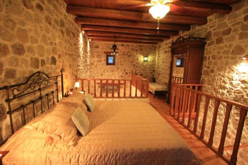 a bedroom with a bed in a stone wall at Lithos Traditional Guest Houses in Xerokampos