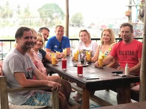 a group of people sitting around a wooden table at ST 63 Home Stay & Tour Kampong Khleang in Kâmpóng Khleăng