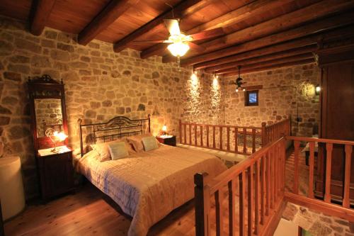 a bedroom with a bed in a stone wall at Lithos Traditional Guest Houses in Xerokampos