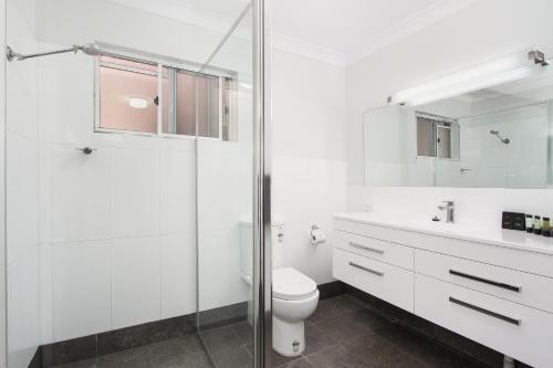 a white bathroom with a toilet and a glass shower at Quality Inn Ashby House Tamworth in Tamworth
