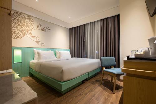 a bedroom with a large bed and a large window at Hotel Santika Garut in Garut