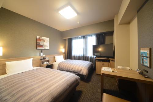 a hotel room with two beds and a flat screen tv at Hotel Route Inn Kasai Hojonoshuku in Kasai