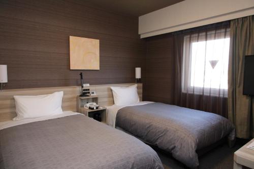 a hotel room with two beds and a window at Hotel Route-Inn Ishioka in Ishioka