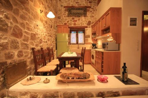 a kitchen with a table and a stone wall at Lithos Traditional Guest Houses in Xerokampos