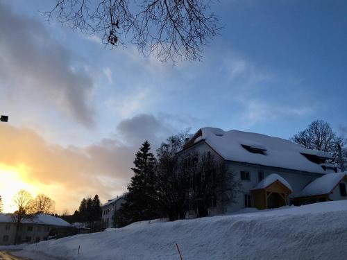 a house covered in snow with the sunset in the background at Jurabelle in La Côte-aux-Fées