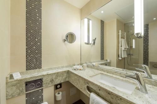 a bathroom with a sink and a mirror at Best Western Plus Hotel Sydney Opera in Paris
