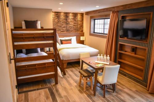 a bedroom with a bunk bed and a desk and a table at Penke Panke Lodge and Apartments in Hakuba