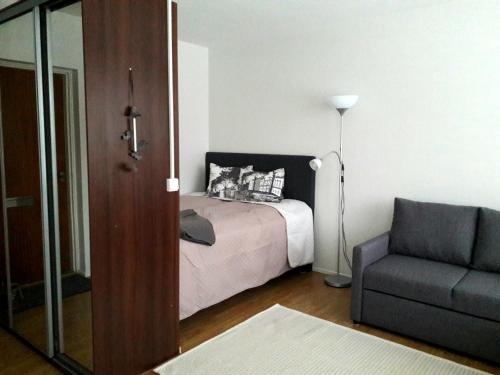 a bedroom with a bed and a couch and a chair at Hamina Orange Apartments Kadetti 1 in Hamina