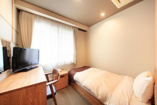 a hotel room with a bed and a television at Posada Suimei in Hakone
