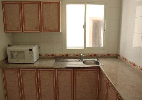 a kitchen with a microwave and a sink at Royal Residence Hotel Apartments in Umm Al Quwain