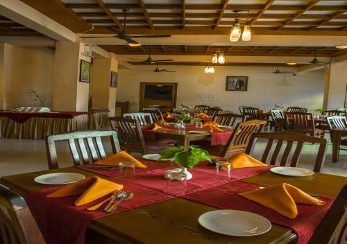 a dining room with a table with yellow napkins and chairs at Oxygen Resorts Thekkady in Thekkady