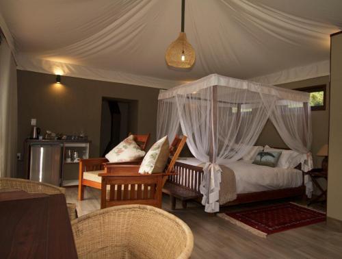 - une chambre avec un lit à baldaquin dans l'établissement Inzalo Safari Lodge, à Réserve animalière Welgevonden