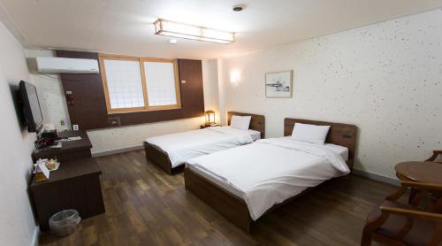 a hotel room with two beds and a television at Jeonju Hansung hotel in Jeonju