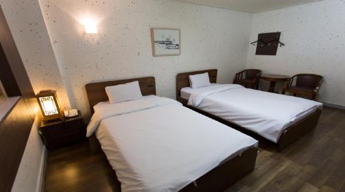 a hotel room with two beds and chairs at Jeonju Hansung hotel in Jeonju