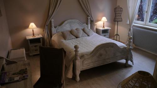 ein Schlafzimmer mit einem weißen Bett und zwei Lampen an Tischen in der Unterkunft L'Ecrin des Saveurs in Schwenheim