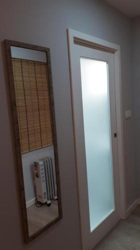 a mirror in a room with a window and a radiator at Casinha do Cedro in Baião