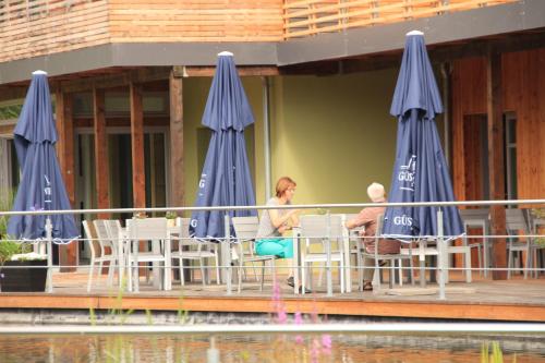 a man and woman sitting at a table with blue umbrellas at An der Metow-Ferienpark Hotel in Plau am See