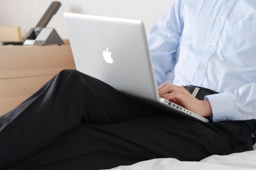 a person sitting on a bed using a laptop computer at Hakata Tokyu REI Hotel in Fukuoka