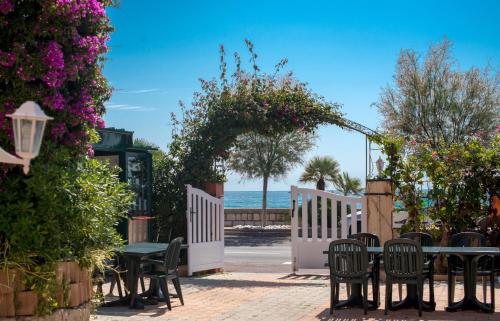 a patio with a table and chairs and flowers at Hotel et Appartements Reine D'Azur in Roquebrune-Cap-Martin