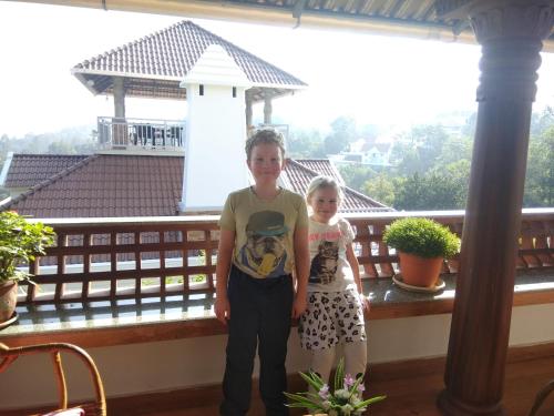 a boy and a girl standing on a balcony at Zenha Resorts in Munnar