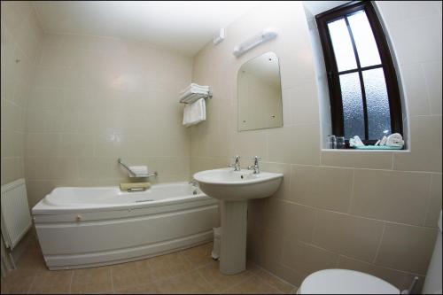 a bathroom with a sink and a tub and a toilet at All the Twos Lodge in Clifden