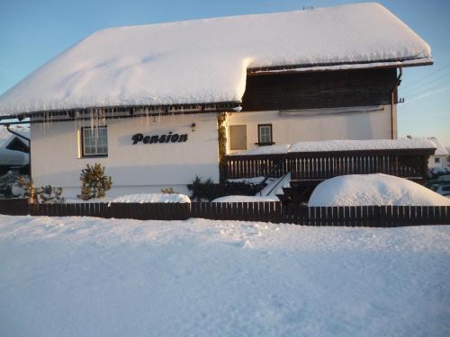 a house covered in snow with a fence at Pension Pugner in Vysoké nad Jizerou