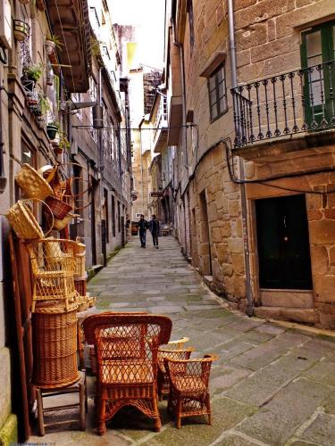 an alley with chairs and tables on a street at Hostal la Colegiata in Vigo