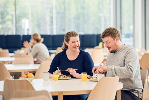 a man and woman sitting at a table eating food at Cathinka Guldbergs Hotell Gardermoen in Jessheim