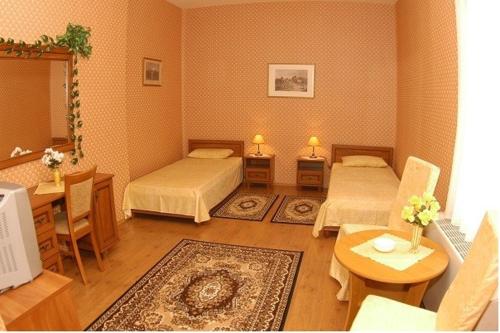 a room with two beds and a table with a tableablish at Peron Panzió in Debrecen