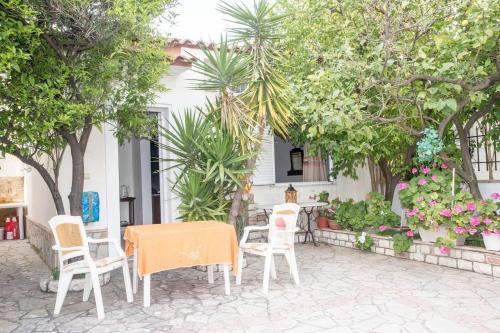 a table and chairs on a patio with trees at On the Beach - Akroyali Family Home in Akrogiali