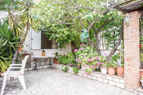 a patio with a chair and flowers in pots at On the Beach - Akroyali Family Home in Akrogiali