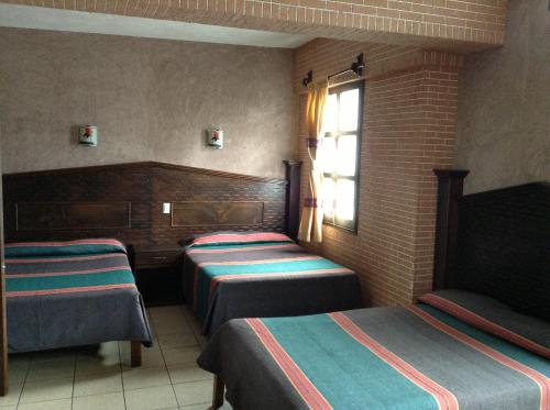 a hotel room with three beds and a window at Hotel Regis in Uruapan del Progreso