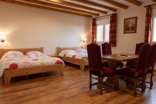 1 dormitorio con 2 camas, mesa y sillas en Relais du Klevener en Heiligenstein