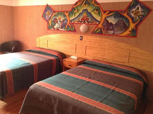 a bedroom with two beds and a painting on the wall at Hotel Regis in Uruapan del Progreso