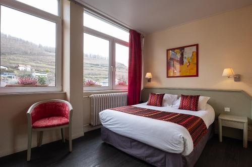 a hotel room with a bed and two windows at The Originals City Hotel de l Ange Guebwiller in Guebwiller